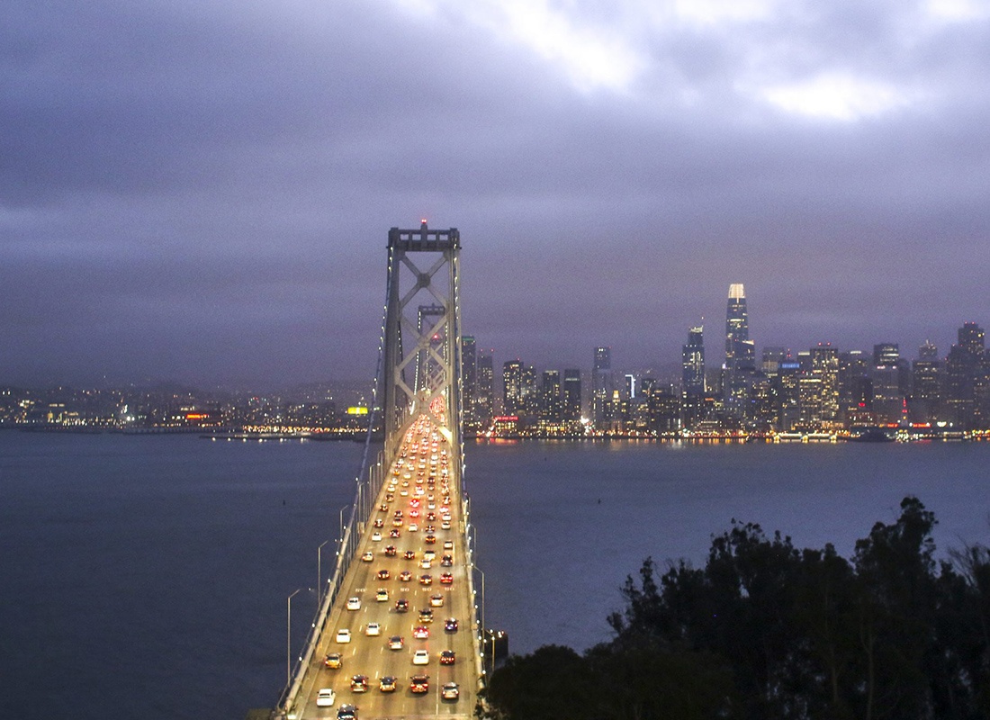 About Our Agency - Aerial View of The Golden Gate Bridge at Night With Many Cars Driving Through it and the City of San Francisco Lit up